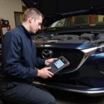 A certified Mazda mechanic using a Centech OBD2 scan tool for diagnosis